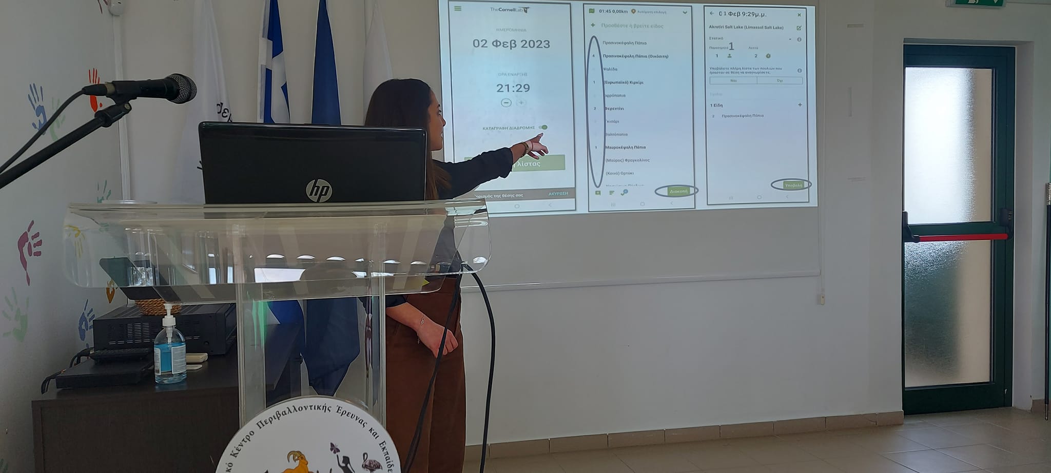A leccturer points at a Powerpoint slide with information in Greek about introducing the Backyard Birdcount to Cyprus